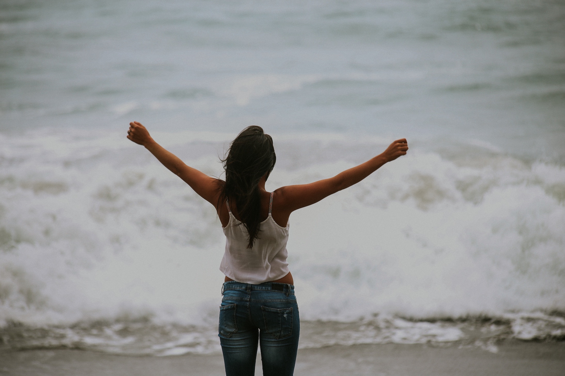 Woman with arms outstretched at ocean. free to be off Suboxone