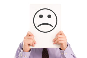 American man holding a picture of a sad face