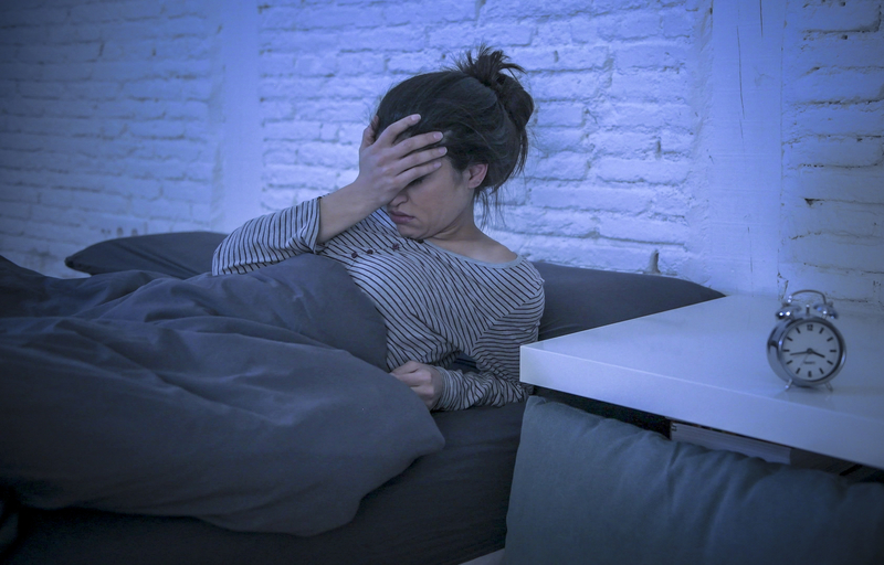 worried woman in bed, head in hand, woke up after relapse