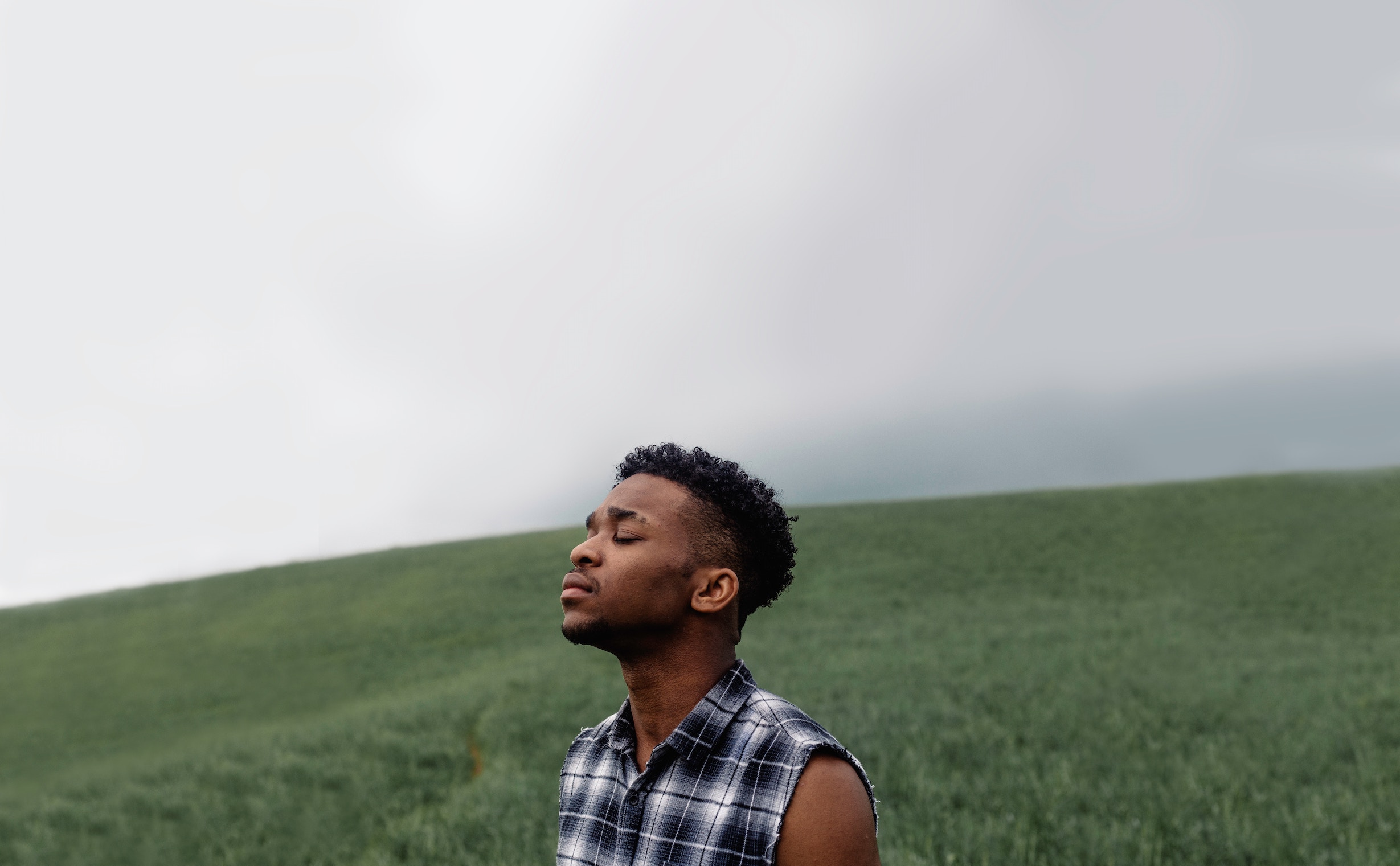 Young man in a field, appears full of emotion, reflecting on suicide prevention