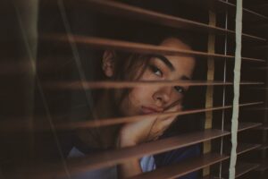 depressed woman looking out window, needs to manage depression