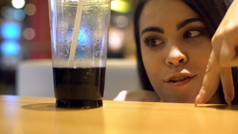Woman's face and fingers moving toward diet soda, addicted to chemicals in food