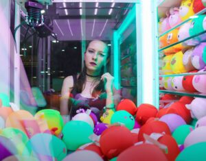Woman looking through glass of claw game, wishing she could tell her parents about addiction