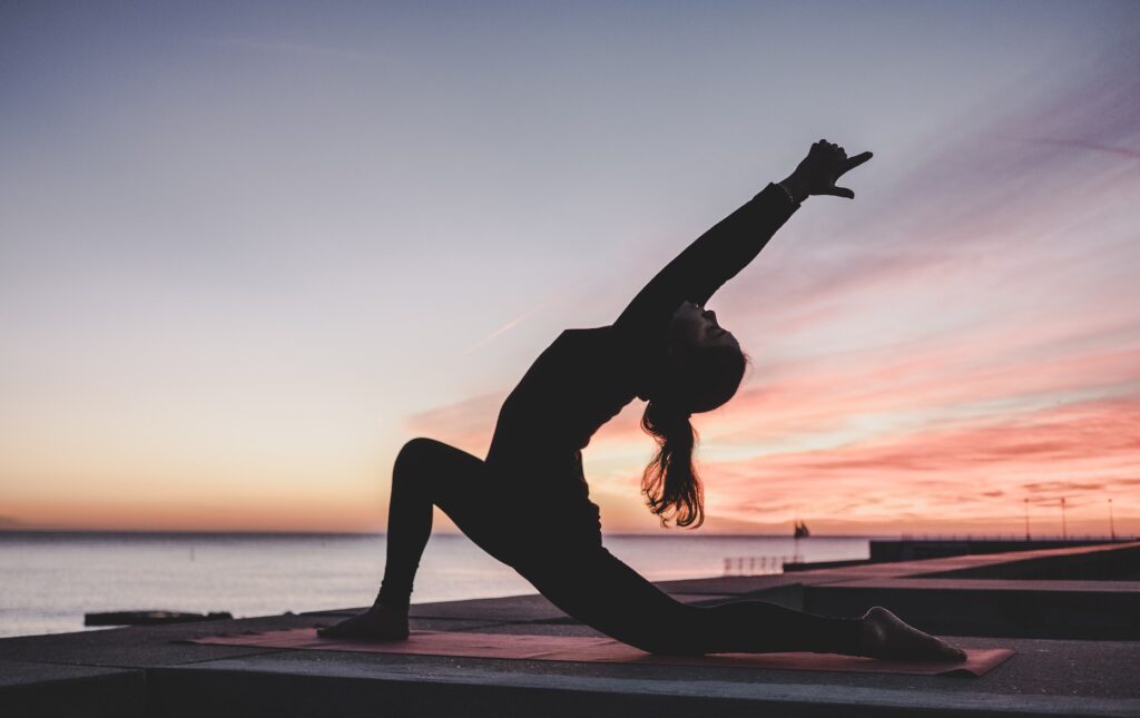 Woman in yoga post outside at sunset, yoga for healing addiction