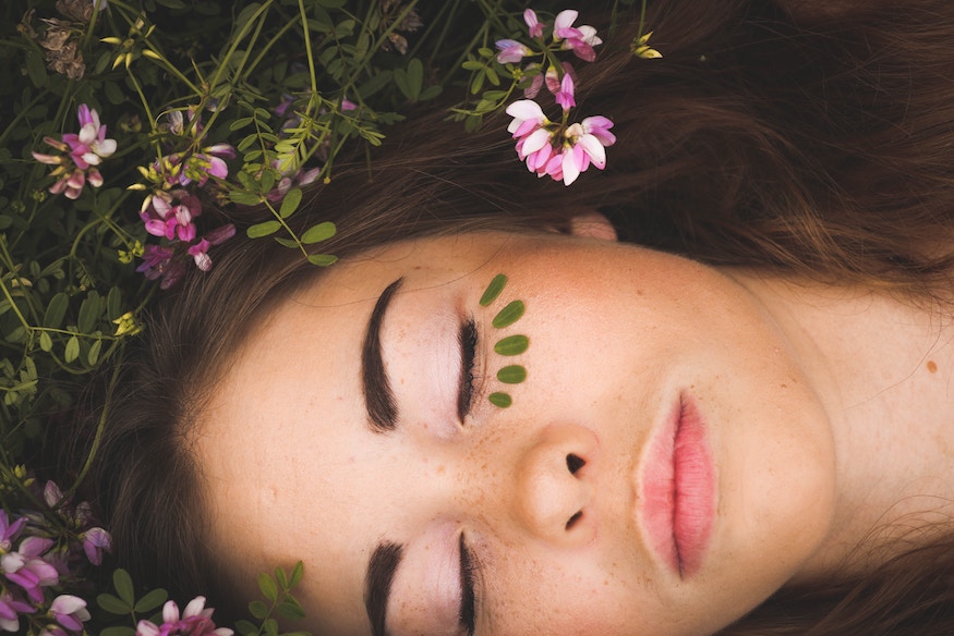 Young woman lying on grass with eyes closed, relief from anxiety, panic attacks in childhood