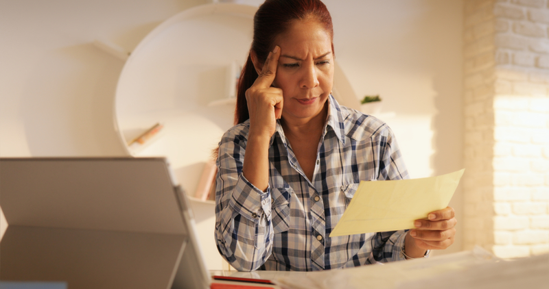 Woman looking at paperwork, frowning, remembering to keep her side of the street clean in recovery.