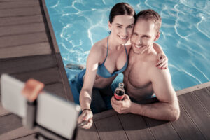 Couple in a pool taking a selfie on a first date with a sober alcoholic.