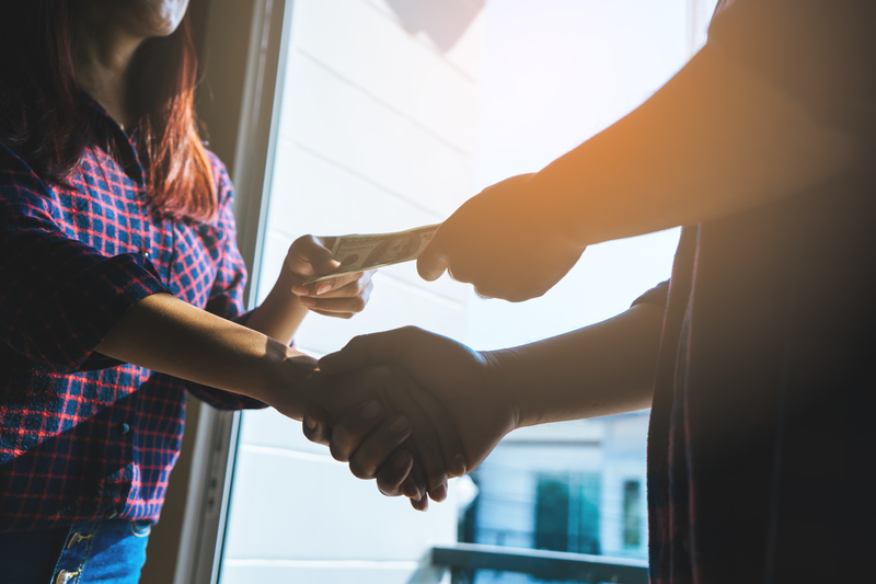 broker giving kickback money to a recovering addict, two people exchanging money