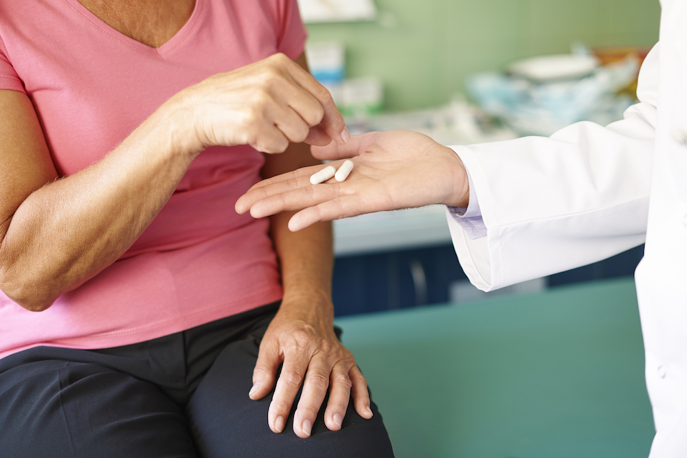 woman taking opioid pill from doctor