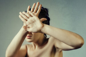 woman holding her hands in front of her face in shame