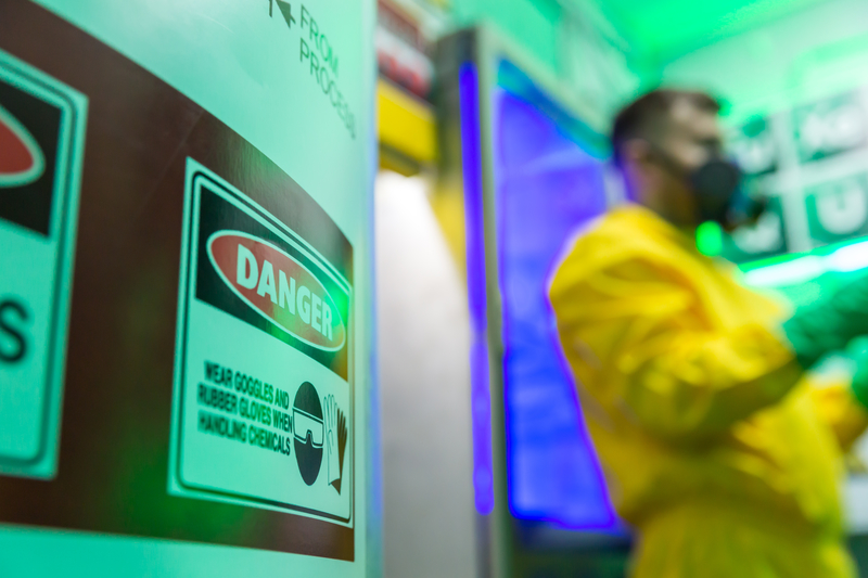 Man in lab in yellow suit, with chemicals; meth lab