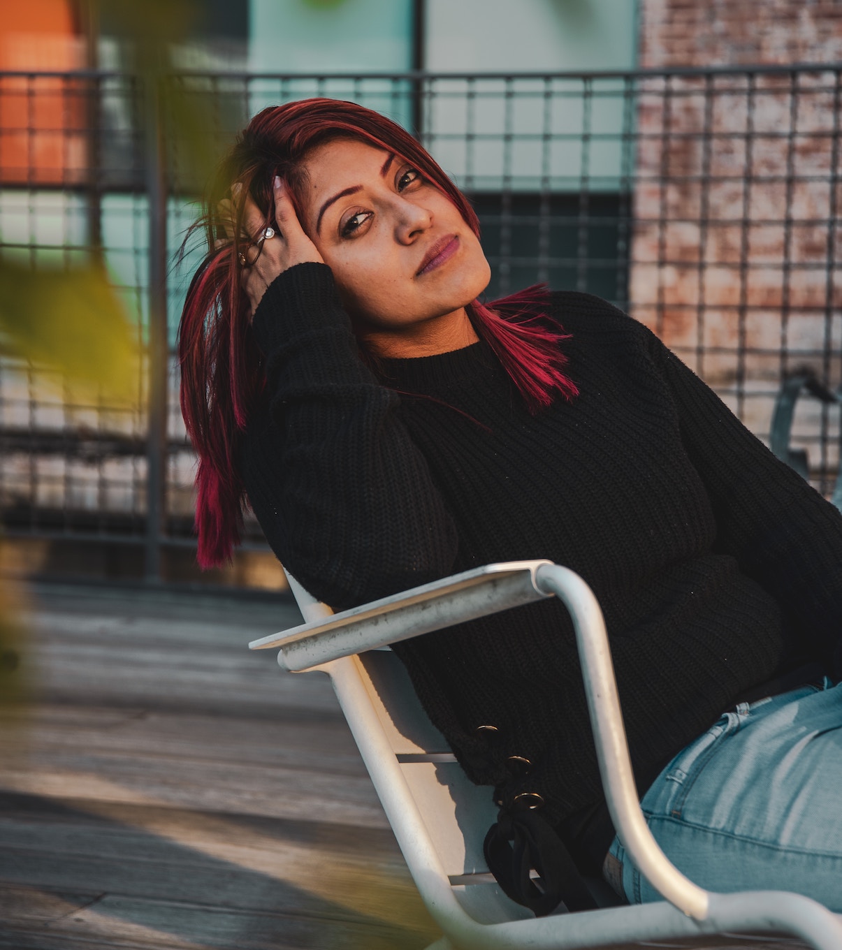 Woman sitting on white chair outside, relaxing, head on hand.