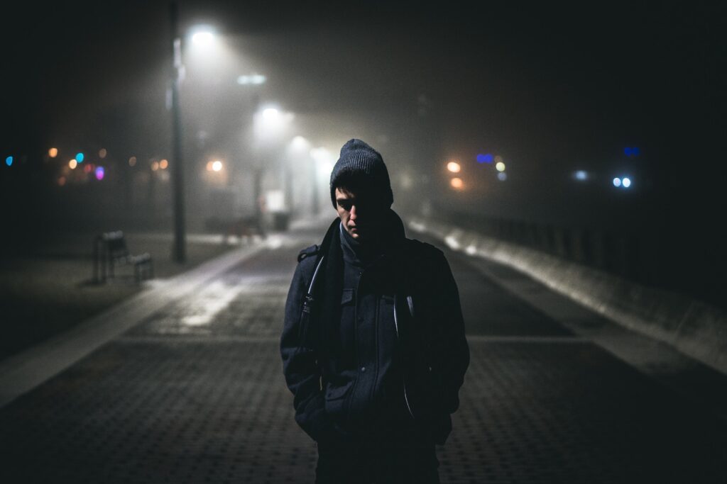 Post-Incarceration Syndrome: Adjusting to Reality After Spending 15 Years in Prison Man alone on a street in hooded jacket, looking down.