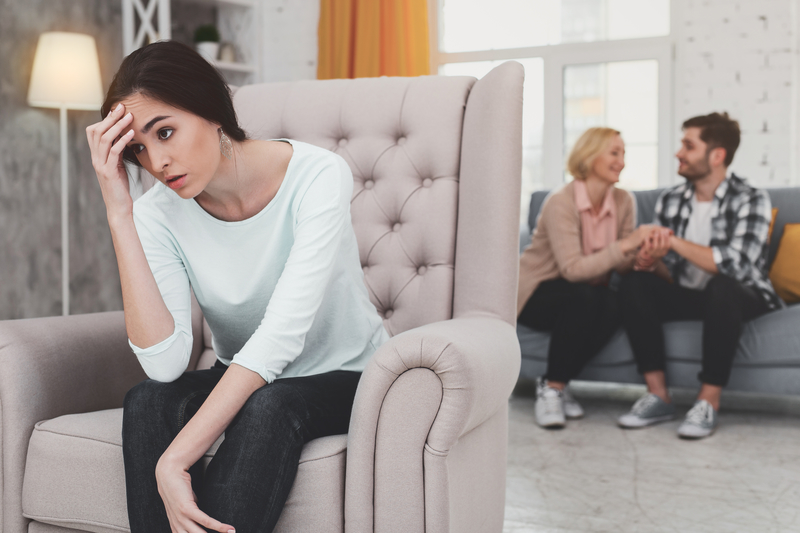 Unhappy woman sits apart from happy family members
