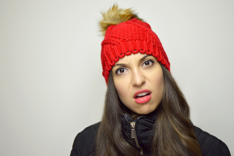 woman in red, knit cap perplexed by Facebook algorithm