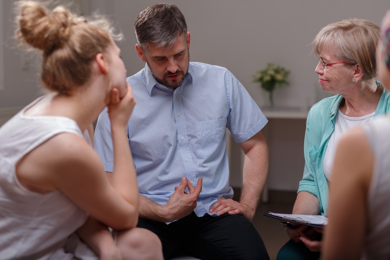A Man speaks while two women listen during group therapy