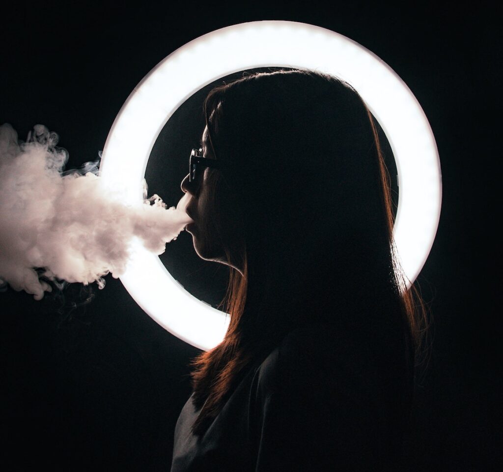 Should I Stop Vaping? Face in silhouette in circle exhaling smoke or vapor, person vaping