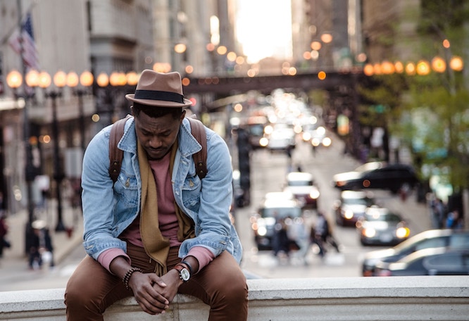 a man sits alone in the city, looking depressed.