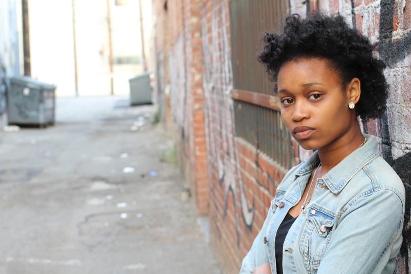 Depressed or annoyed black woman, leaning on a wall