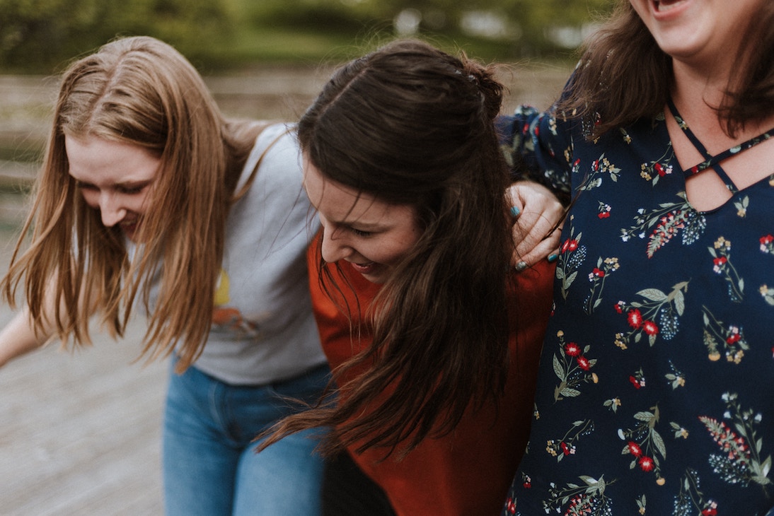Three women arm in arm, happy.