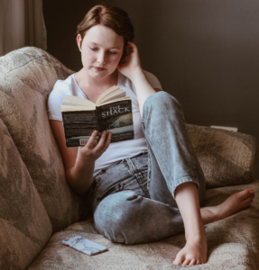 woman reading a book while seated on a couch