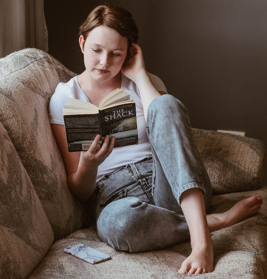 woman reading a book while seated on a couch