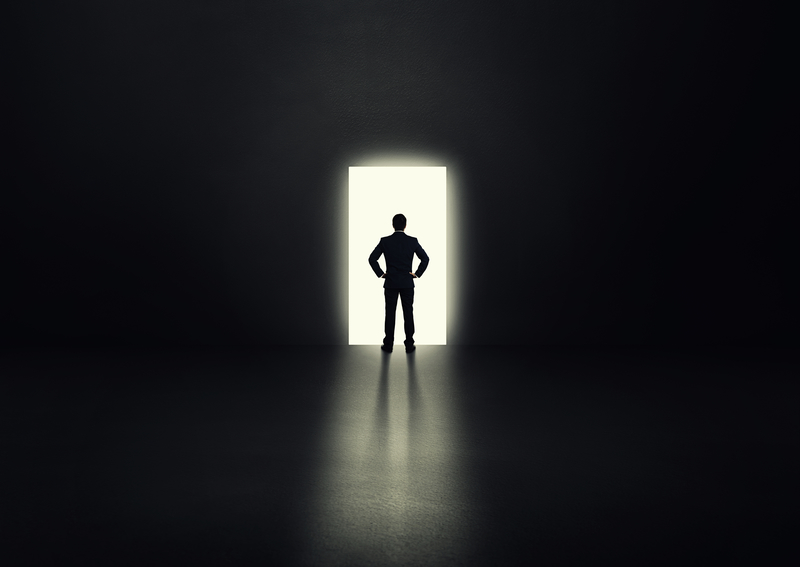 Man silhouetted in lit up doorway in darkness.
