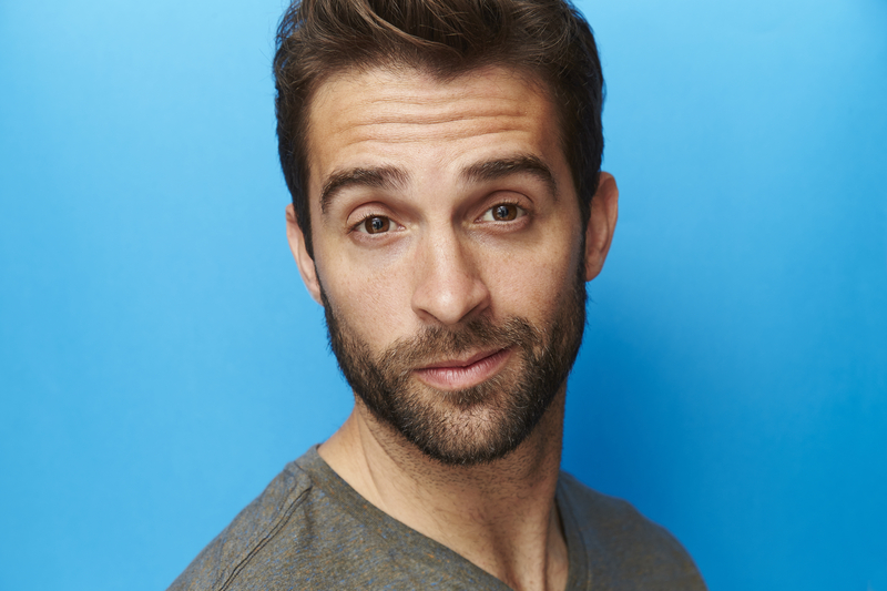 Man with smug expression on blue background.