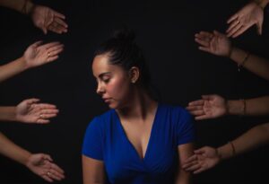 Woman looks to side as various hands reach towards her
