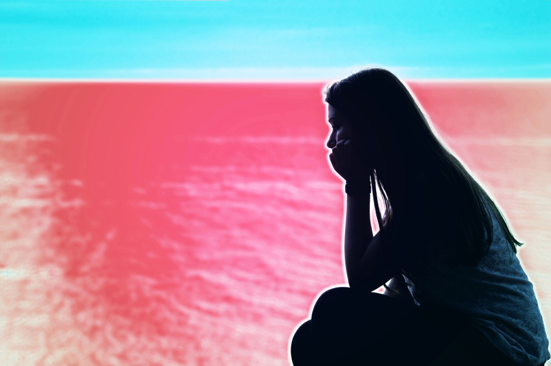 Silhouette of woman sitting with chin in hands, colored background