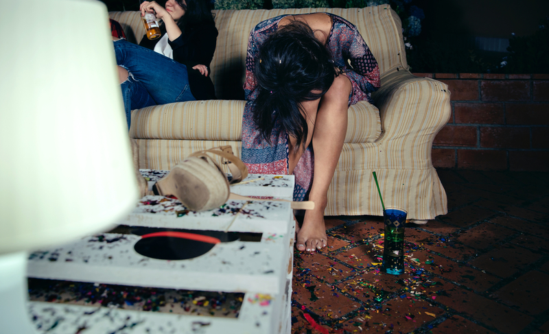 Drunk woman sits doubled over on couch