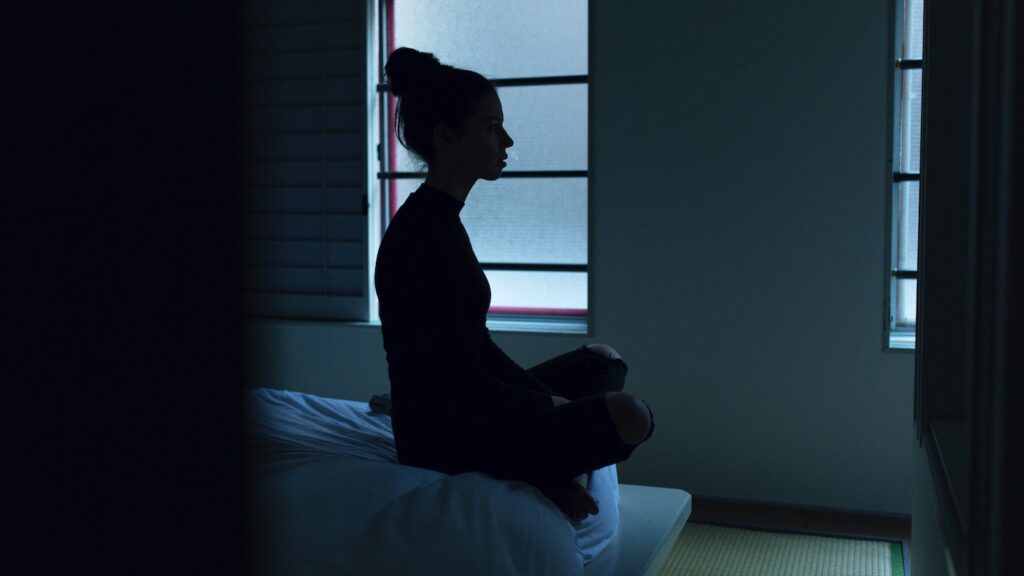 Preventing Opiate Dependency with Mindful Body Awareness Silhouette of woman cross-legged on bed in darkness