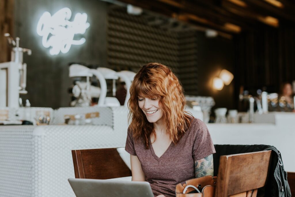 Smiling woman at laptop in empty cafe