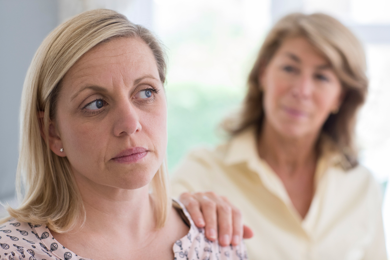Woman with her hand on other woman's shoulder, looking concerned.