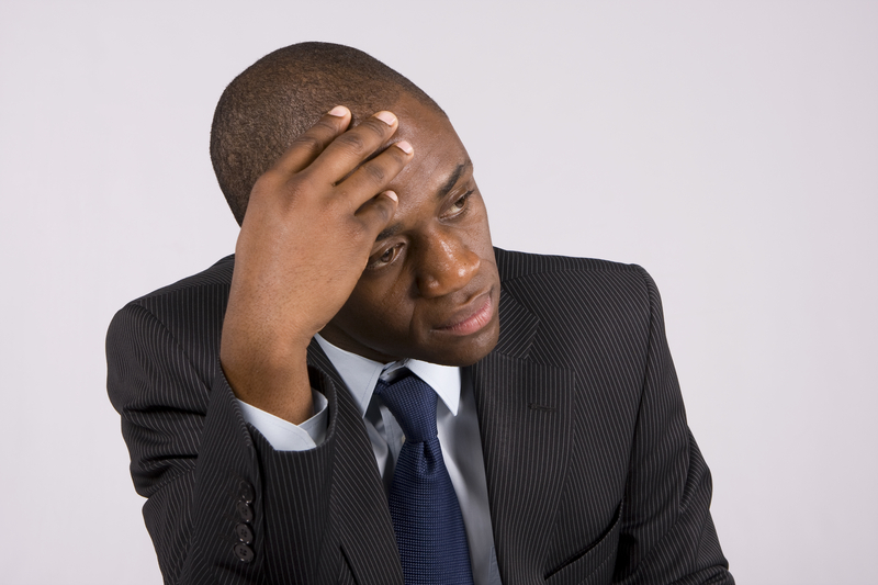 Man in business suit, hand on head.