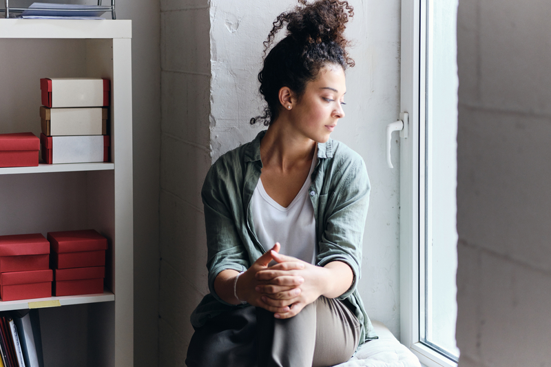 Young woman, thoughtful, looks out a window.