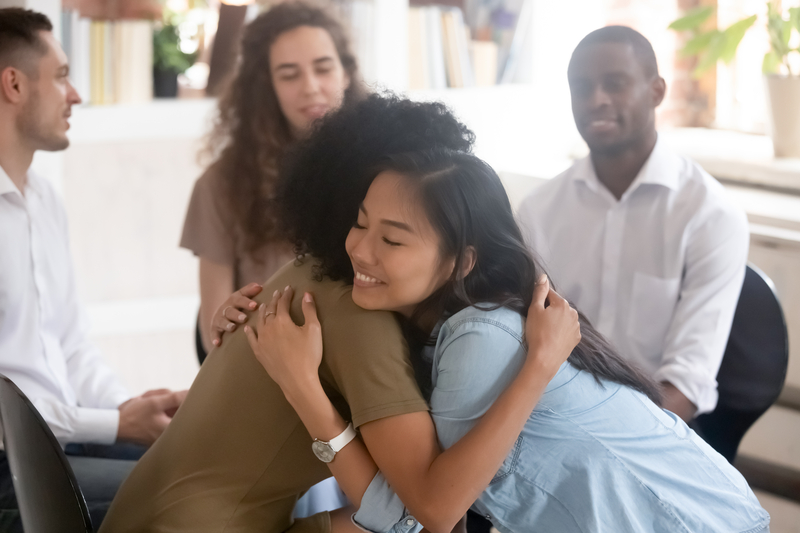 2 women in group therapy embrace