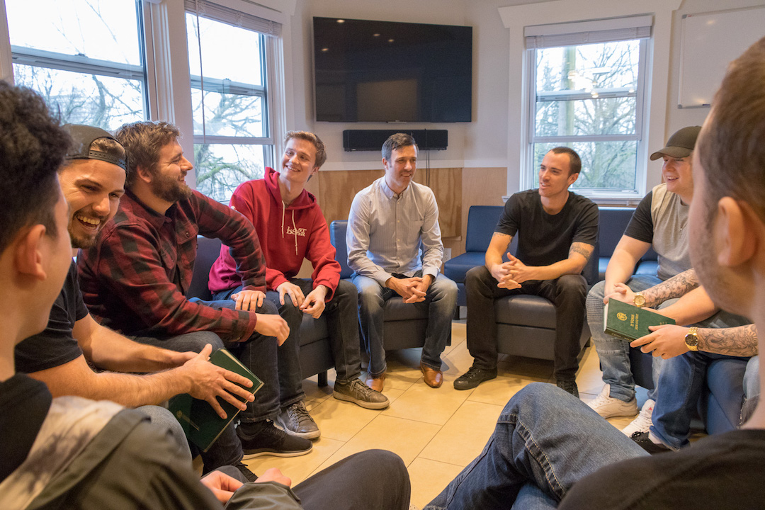 A group of young men in a circle, smiling and laughing.