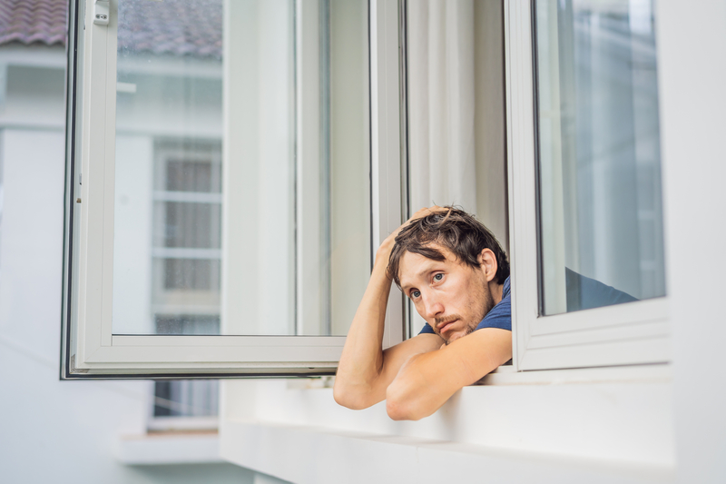 Man looks out window, sad expression