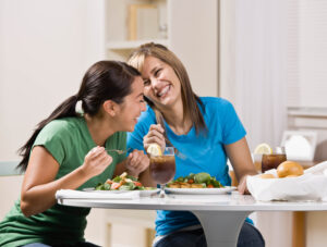 Two women eating a healthy meal and laughing.