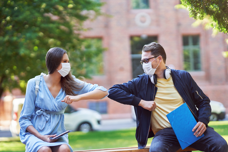 Man and woman touching elbows together on college campus