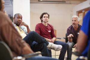 Group therapy or AA meeting: several people sit in folding chairs in a circle