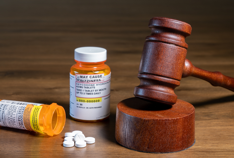 Oxycodone bottle and pills next to courtroom gavel