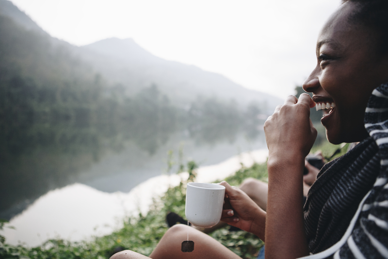 Woman sitting by river and drinking tea