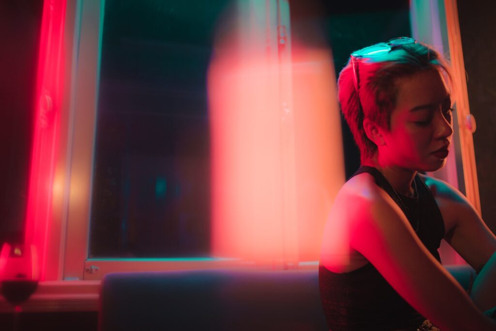 Woman alone in blurry lit background, in bar or club