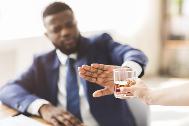 Man in business suit refusing an offered alcoholic drink