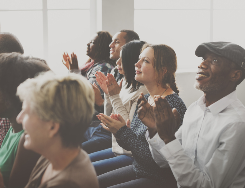 Group of people at a meeting, some clapping
